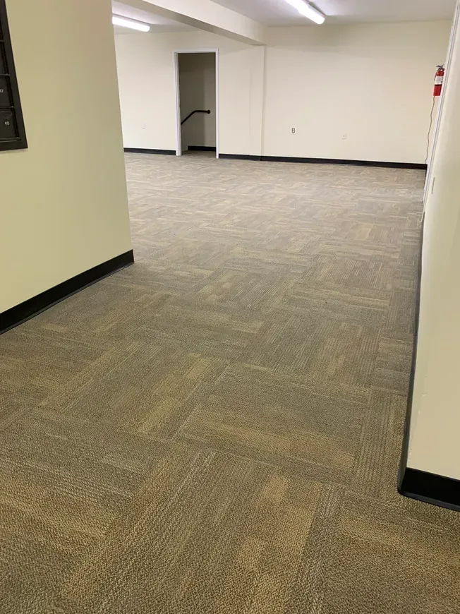 An empty room with a carpeted floor and white walls.