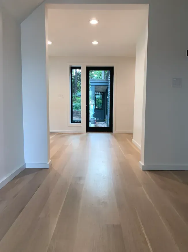 An empty room with hardwood floors and a black door