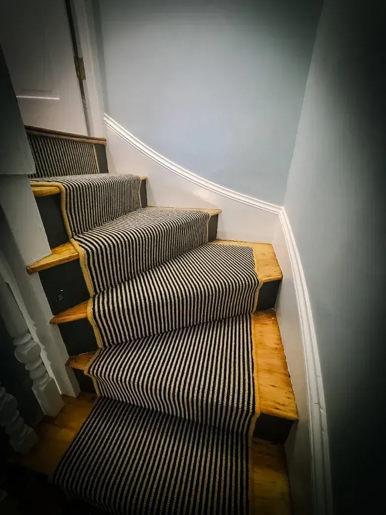 A staircase with a black and white striped carpet on the steps.