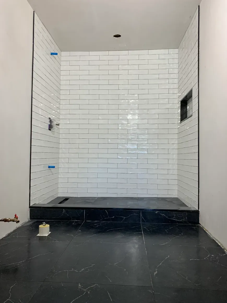 A bathroom with white tiles and a black floor.