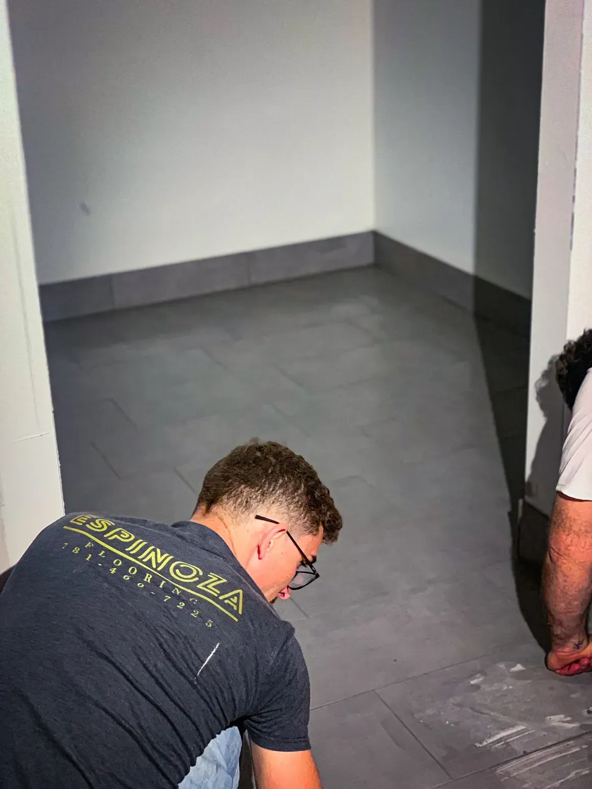 A man is kneeling on a tiled floor in a room.