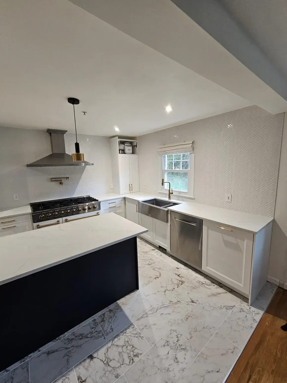 A kitchen with a large island , stove , sink , and dishwasher.
