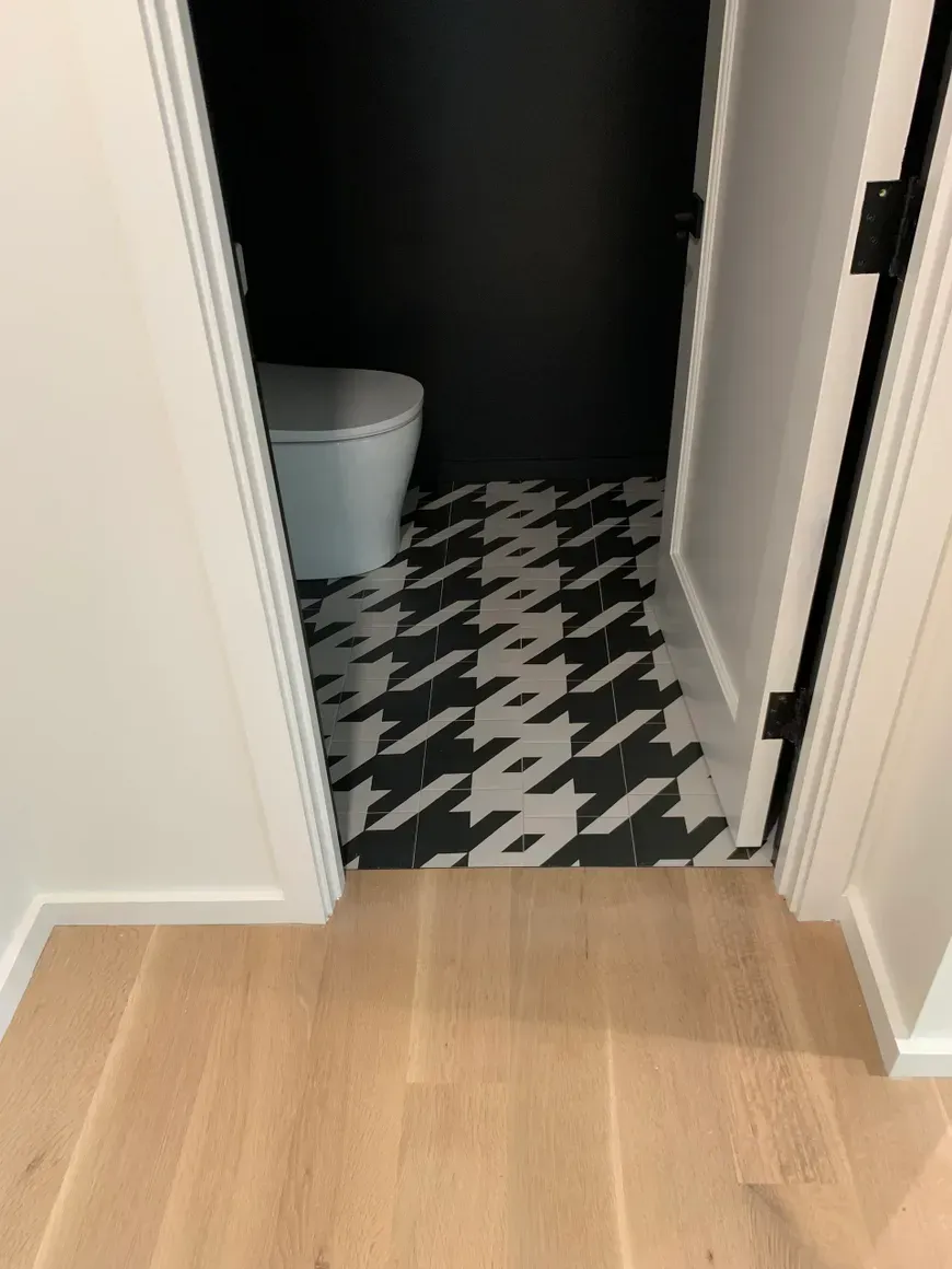 A bathroom with a toilet and a black and white tile floor.