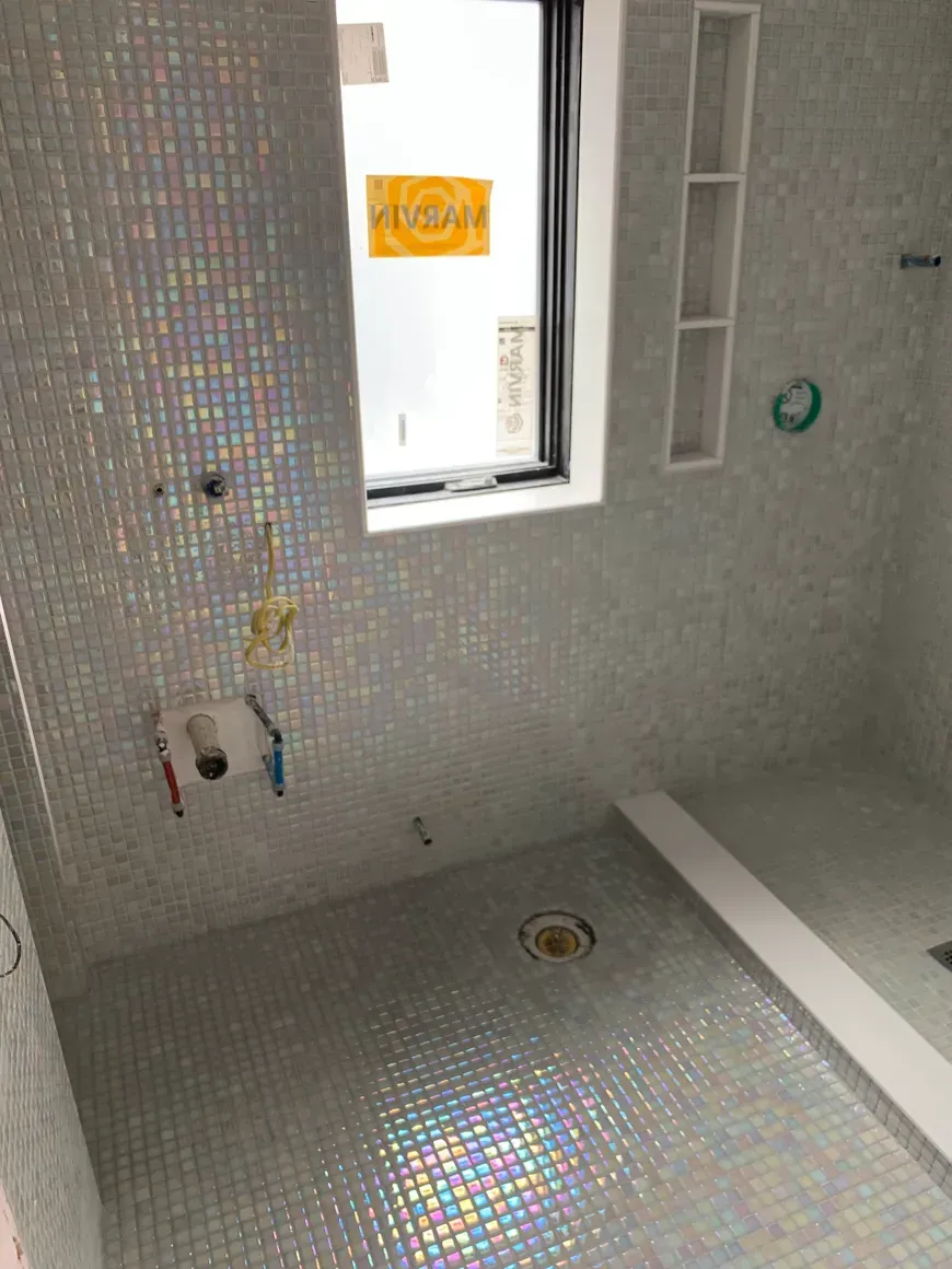 A bathroom with a walk in shower and a window.