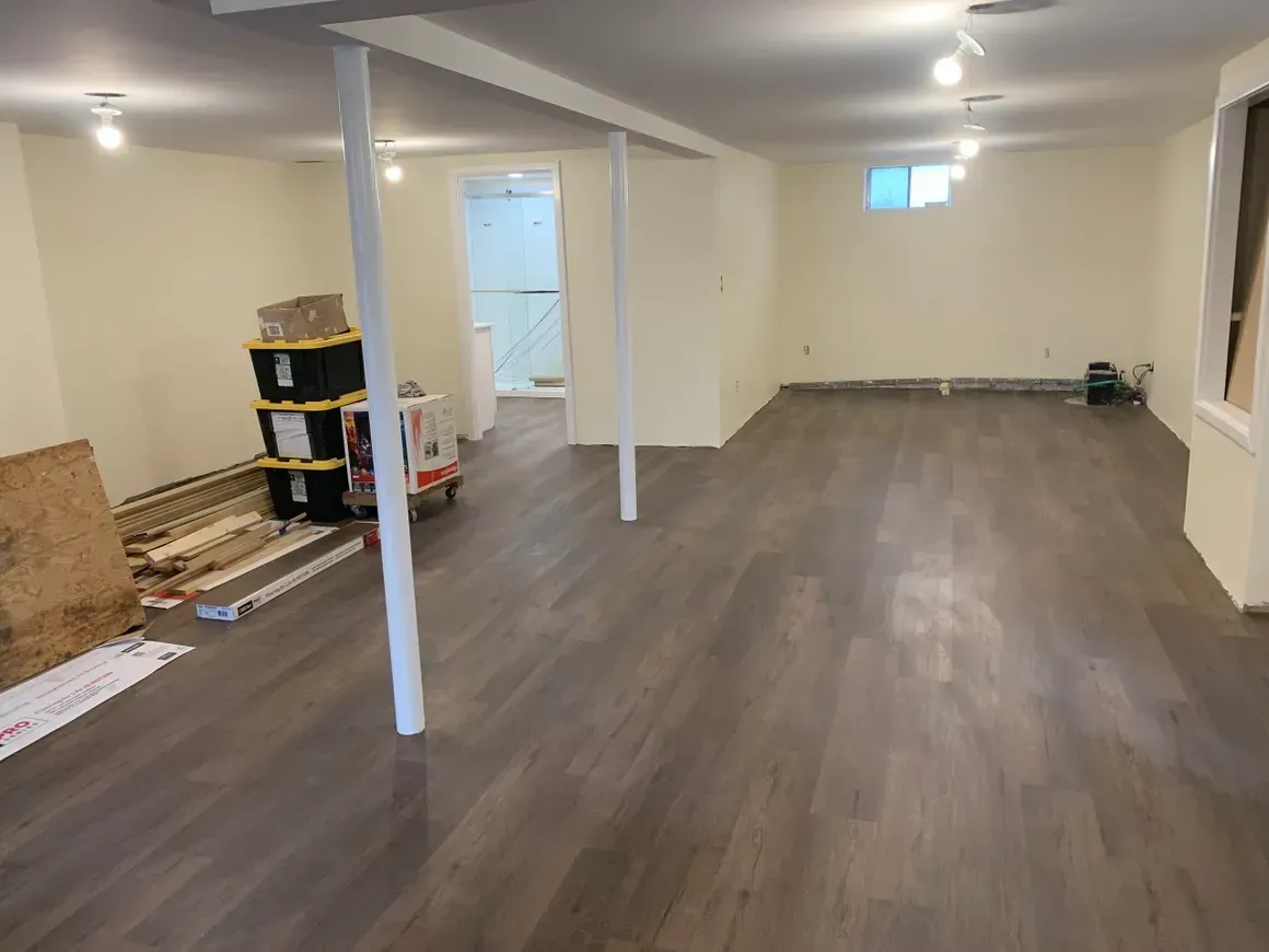 An empty basement with hardwood floors and white walls.