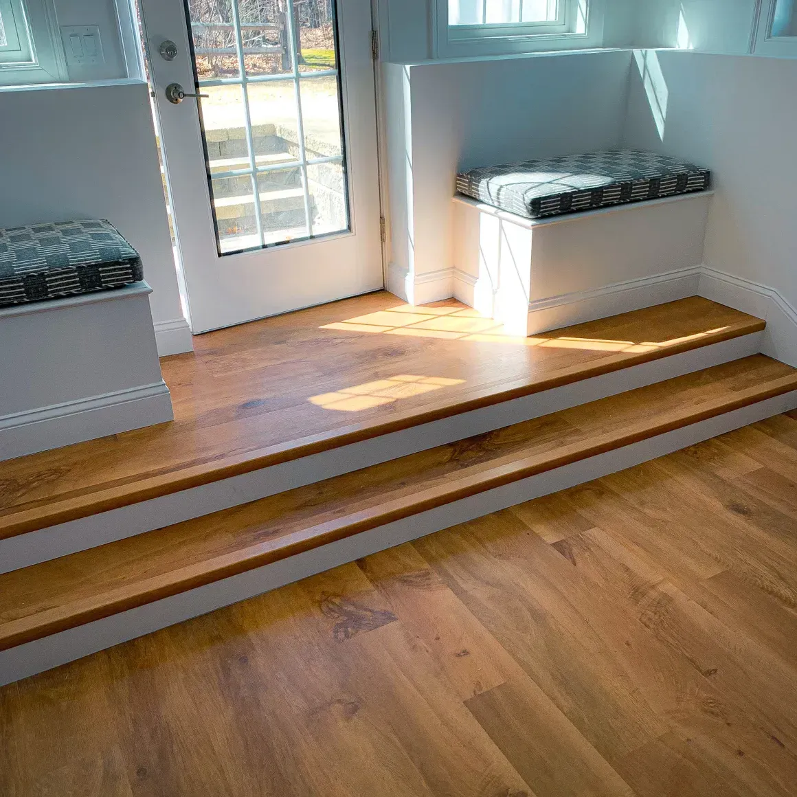 A wooden floor with stairs leading up to a window seat.