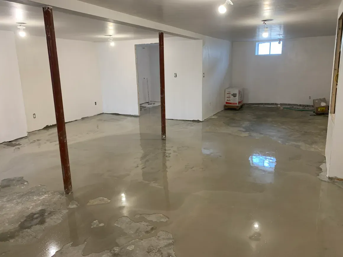 A large empty basement with concrete floors and white walls.