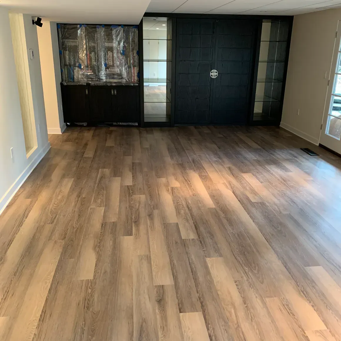 A living room with a wooden floor and a glass cabinet.