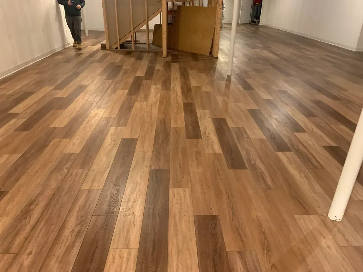 A person is walking down a hallway with a wooden floor.