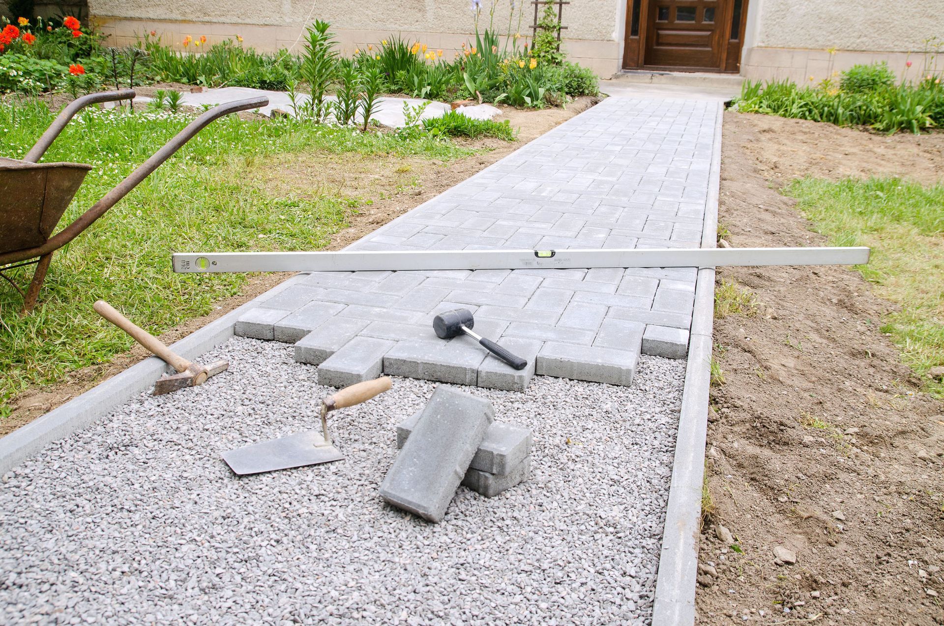 Pathway construction: Gray paving stones, gravel base, tools, level.