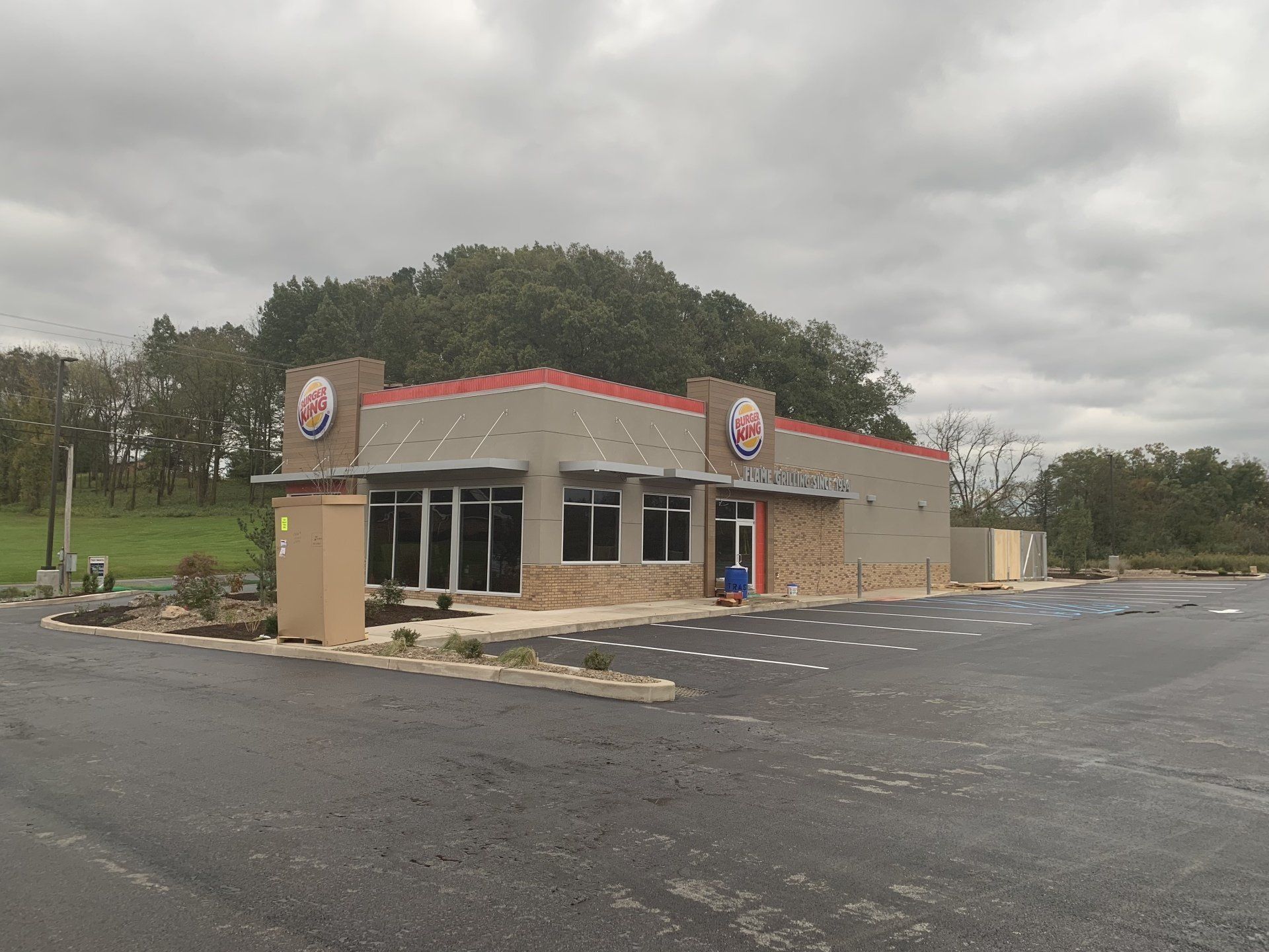 Exterior of a Burger King under construction on a cloudy day; gray siding, red trim, and partially completed parking lot.