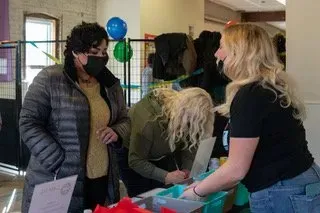 People talking at a table with balloons in a community hall