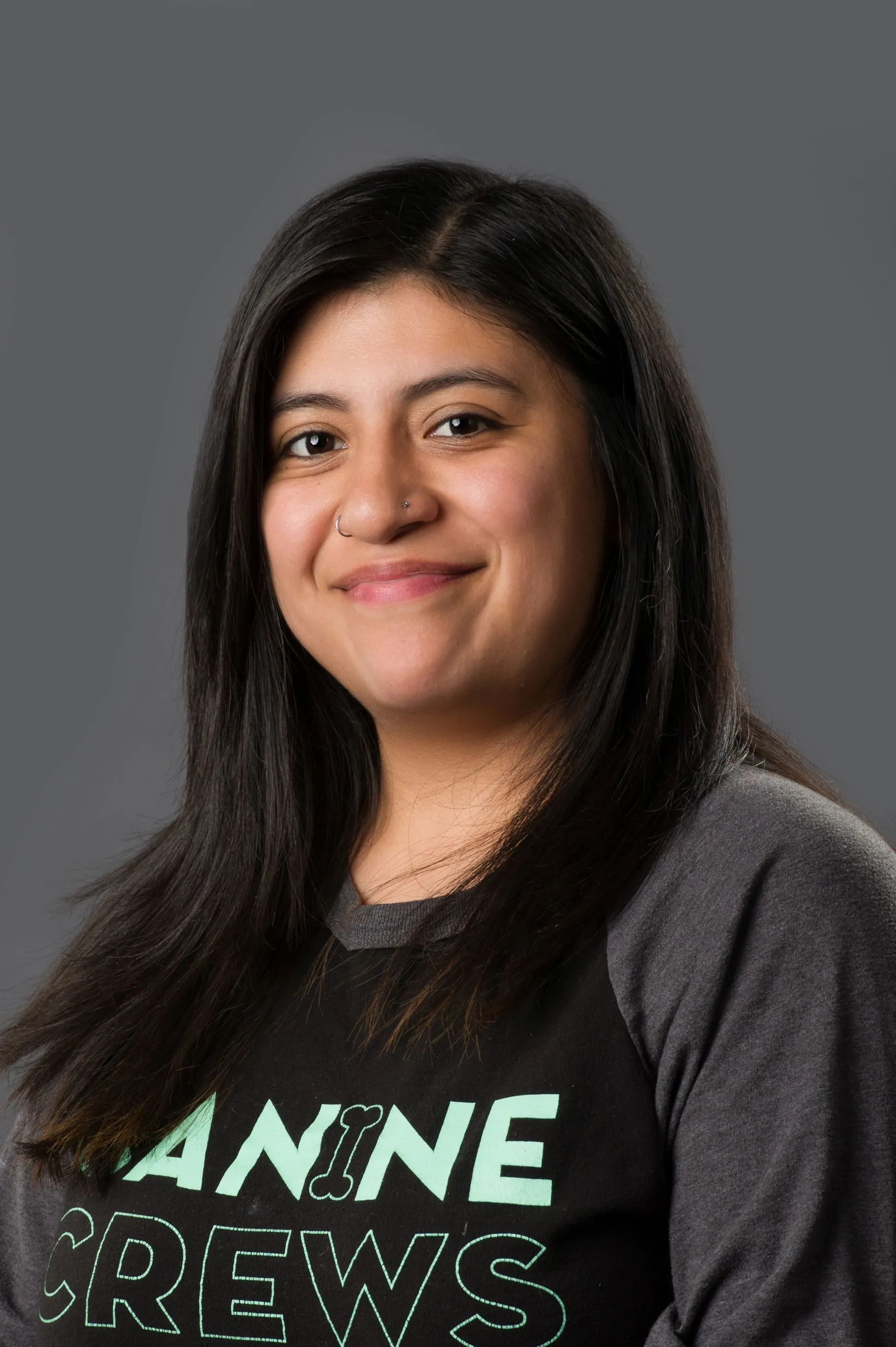 Woman smiling in a dark gray T-shirt against a plain gray background