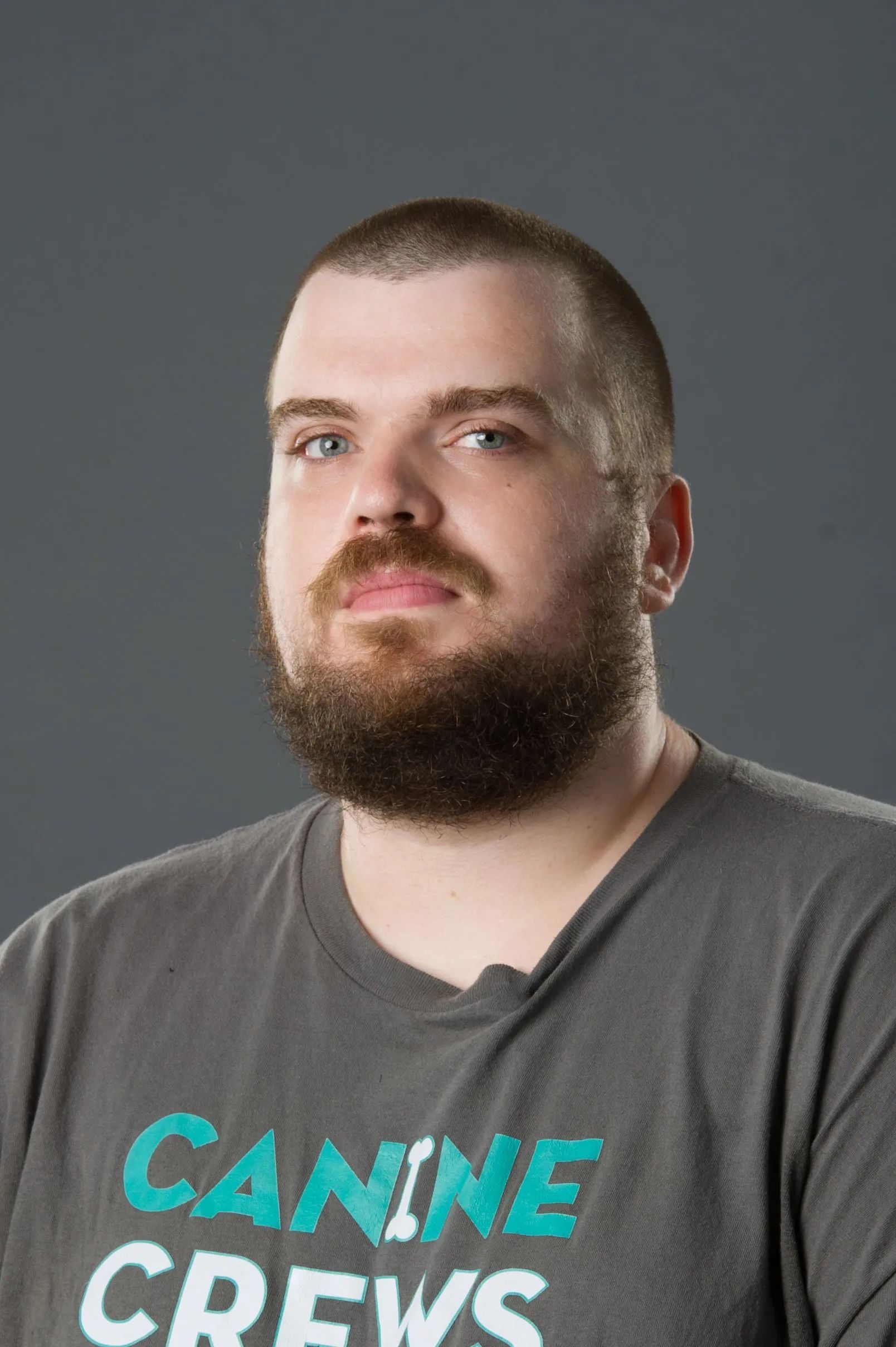 Portrait of a bearded man in a gray T-shirt against a gray background