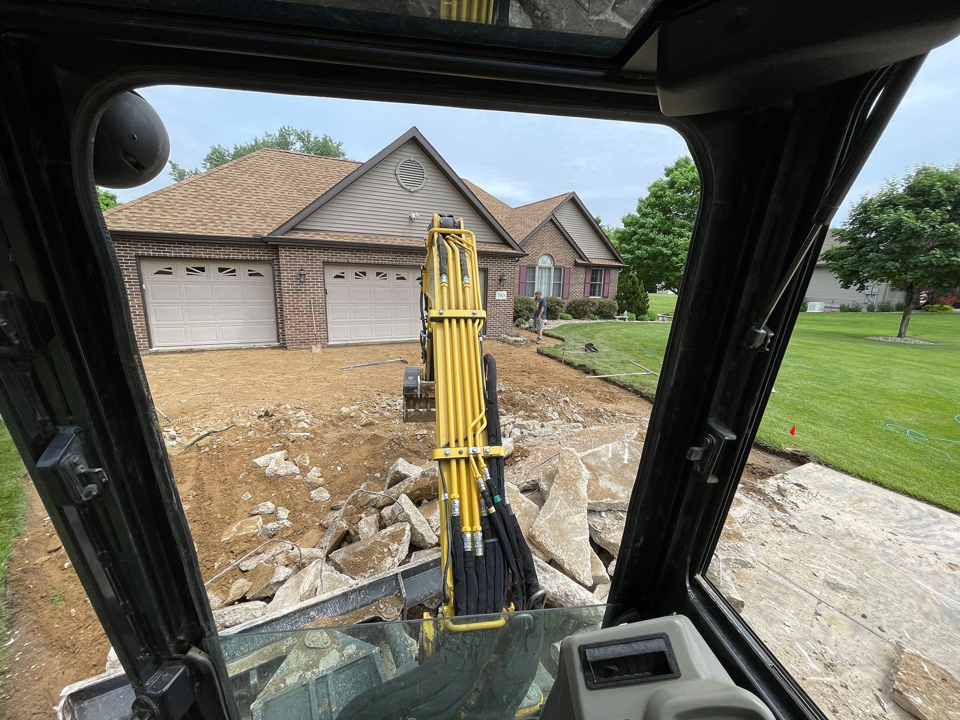 a construction vehicle is driving down a dirt road in front of a house