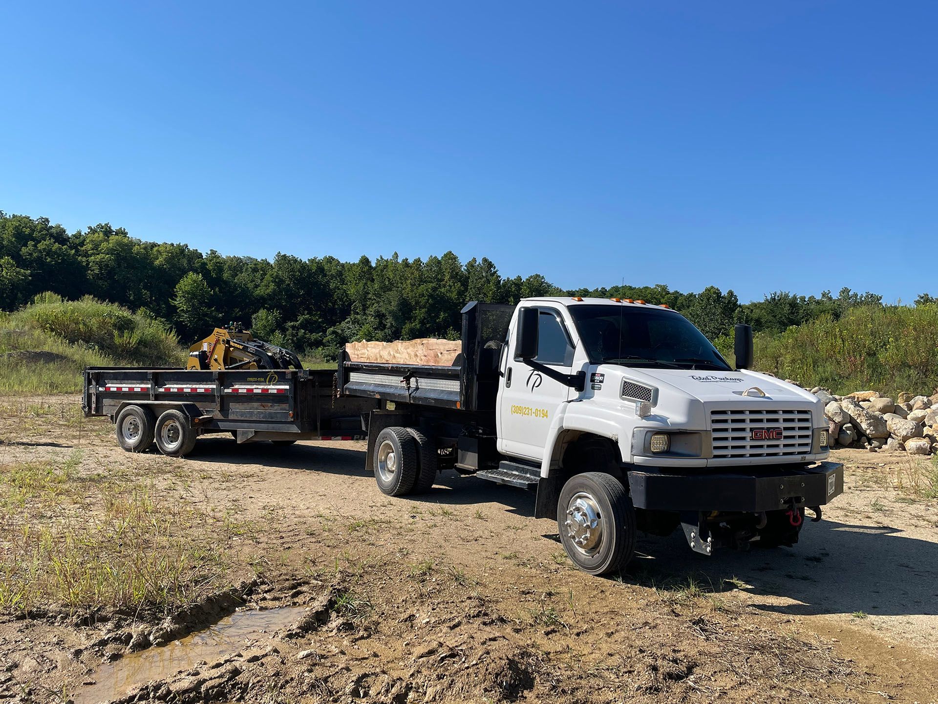 a white dump truck with a trailer attached to it is parked in a dirt field