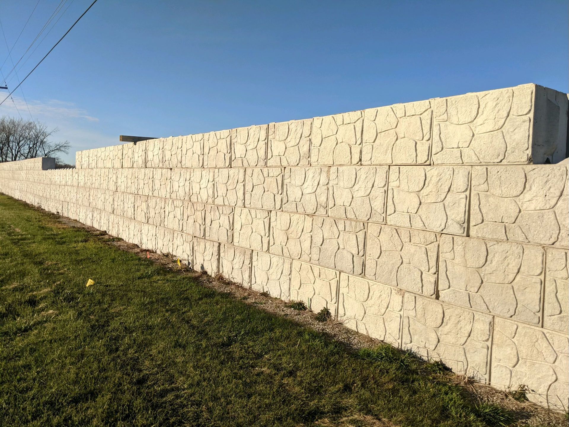 a large white brick wall is sitting in the middle of a grassy field