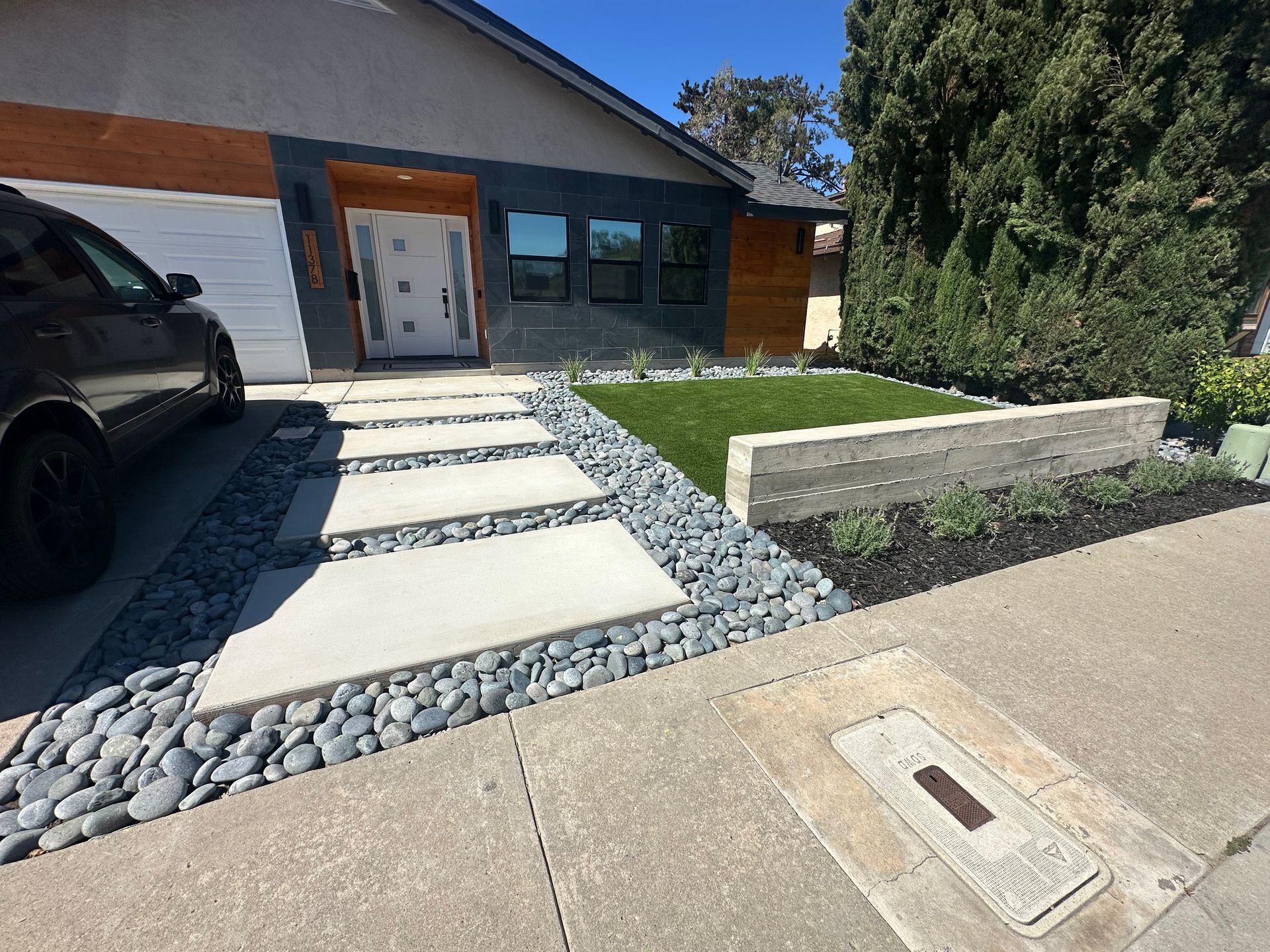 Modern home exterior with a concrete walkway, gray gravel, and landscaped yard.