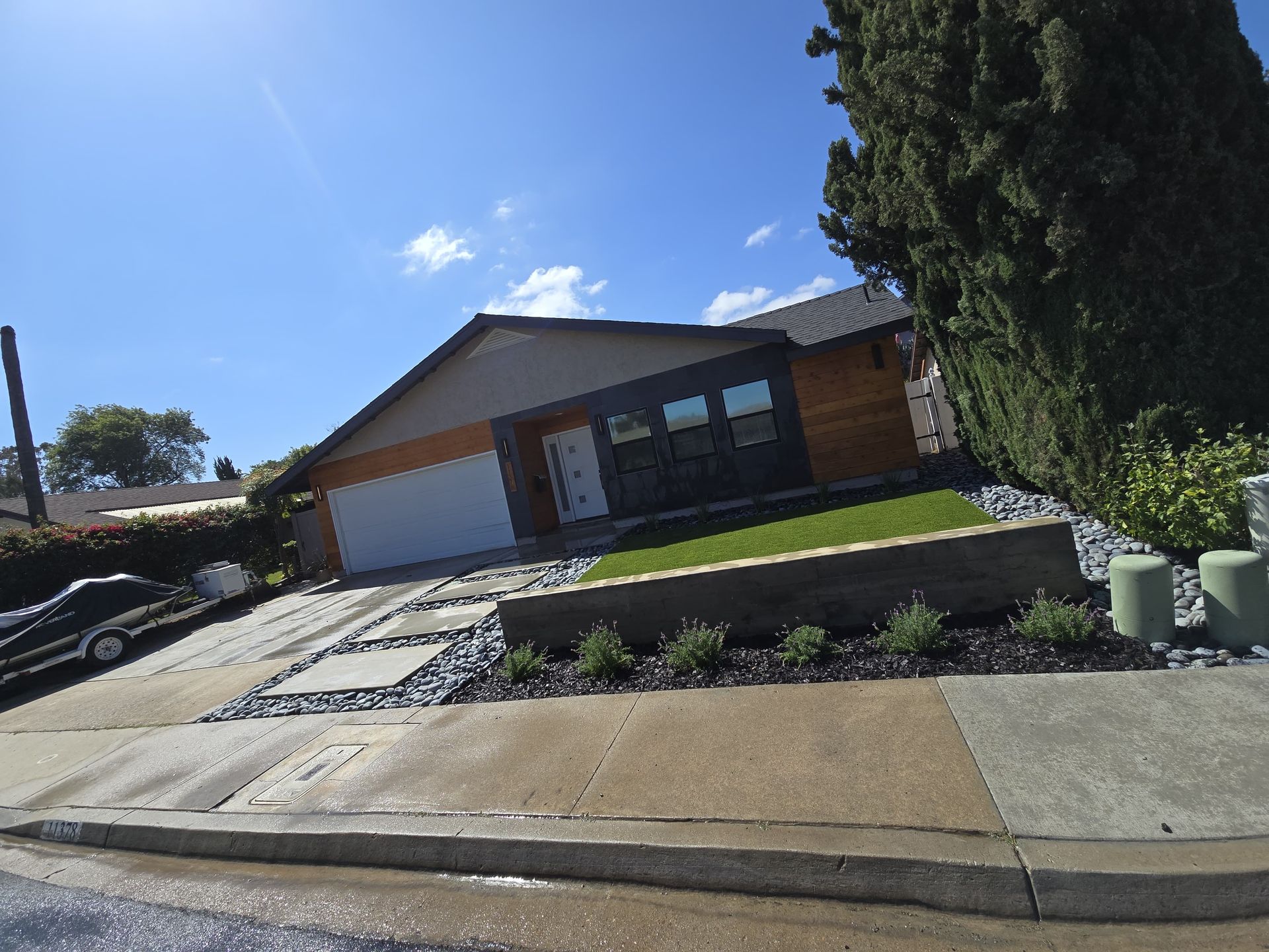 A house with a driveway and landscaped front yard under a bright blue sky.