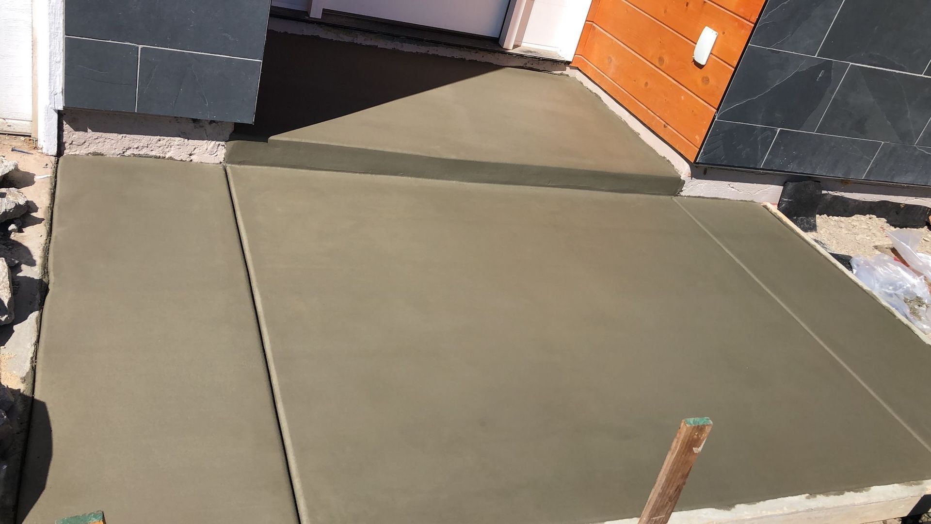 Freshly poured concrete walkway leading to a doorway. The surface is smooth and grey.