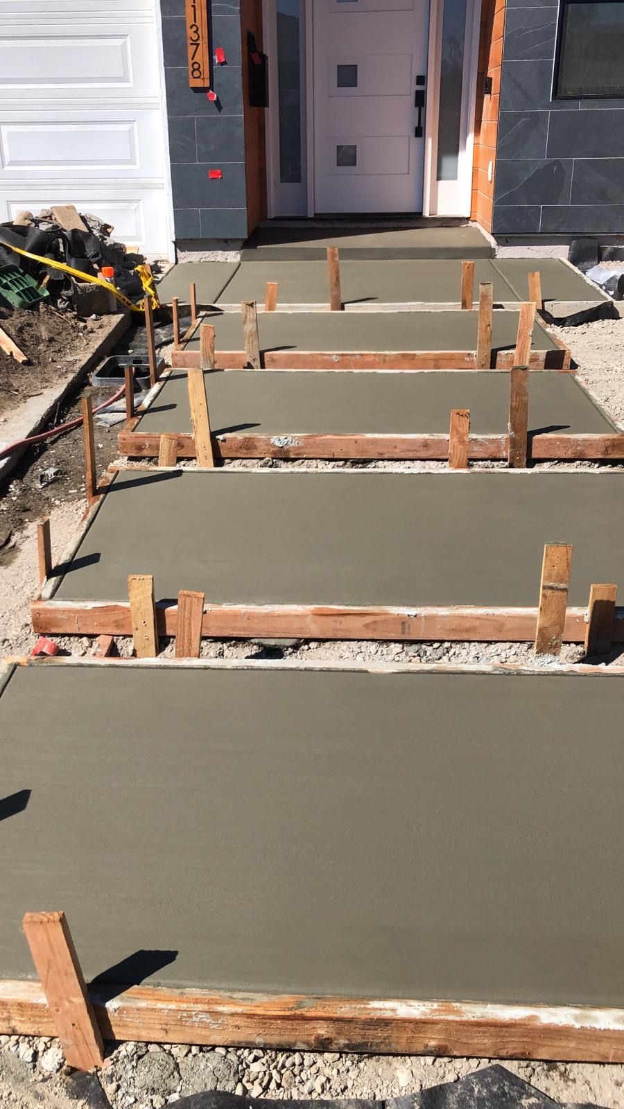 Freshly poured concrete steps leading up to a white front door, surrounded by wooden framing.