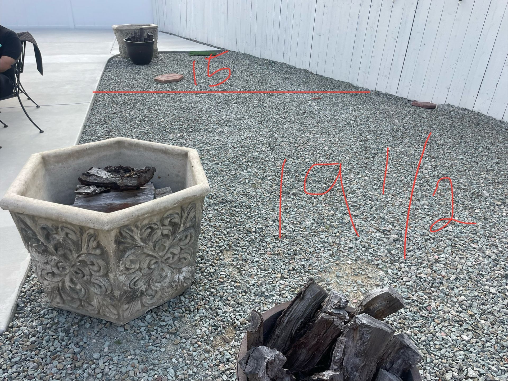 Gravel yard with a large decorative planter, fire pit, and fence. Red lines outline potential garden bed areas.