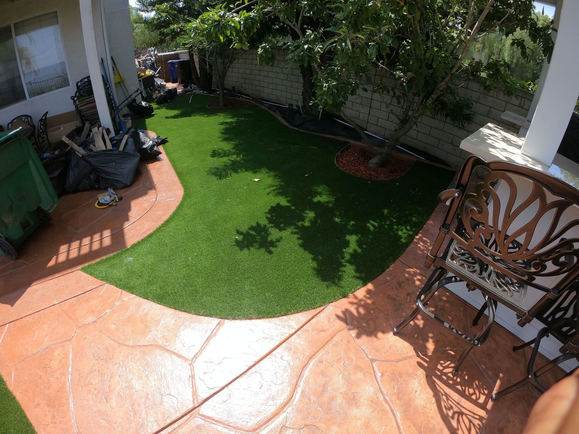 Backyard with stamped concrete patio, artificial grass, and patio furniture.