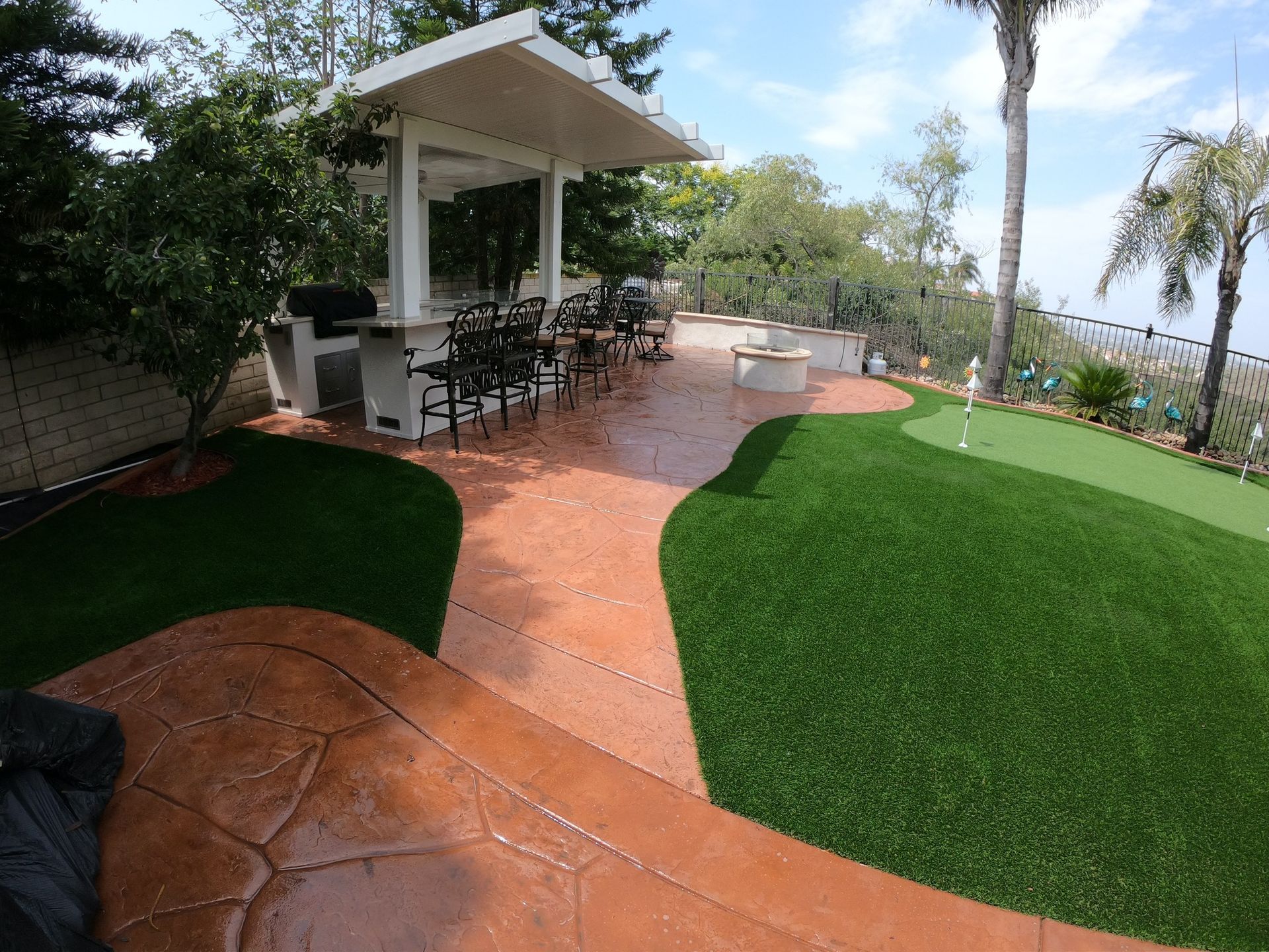 Outdoor patio with barbecue, putting green, seating, and a pergola-covered dining area.