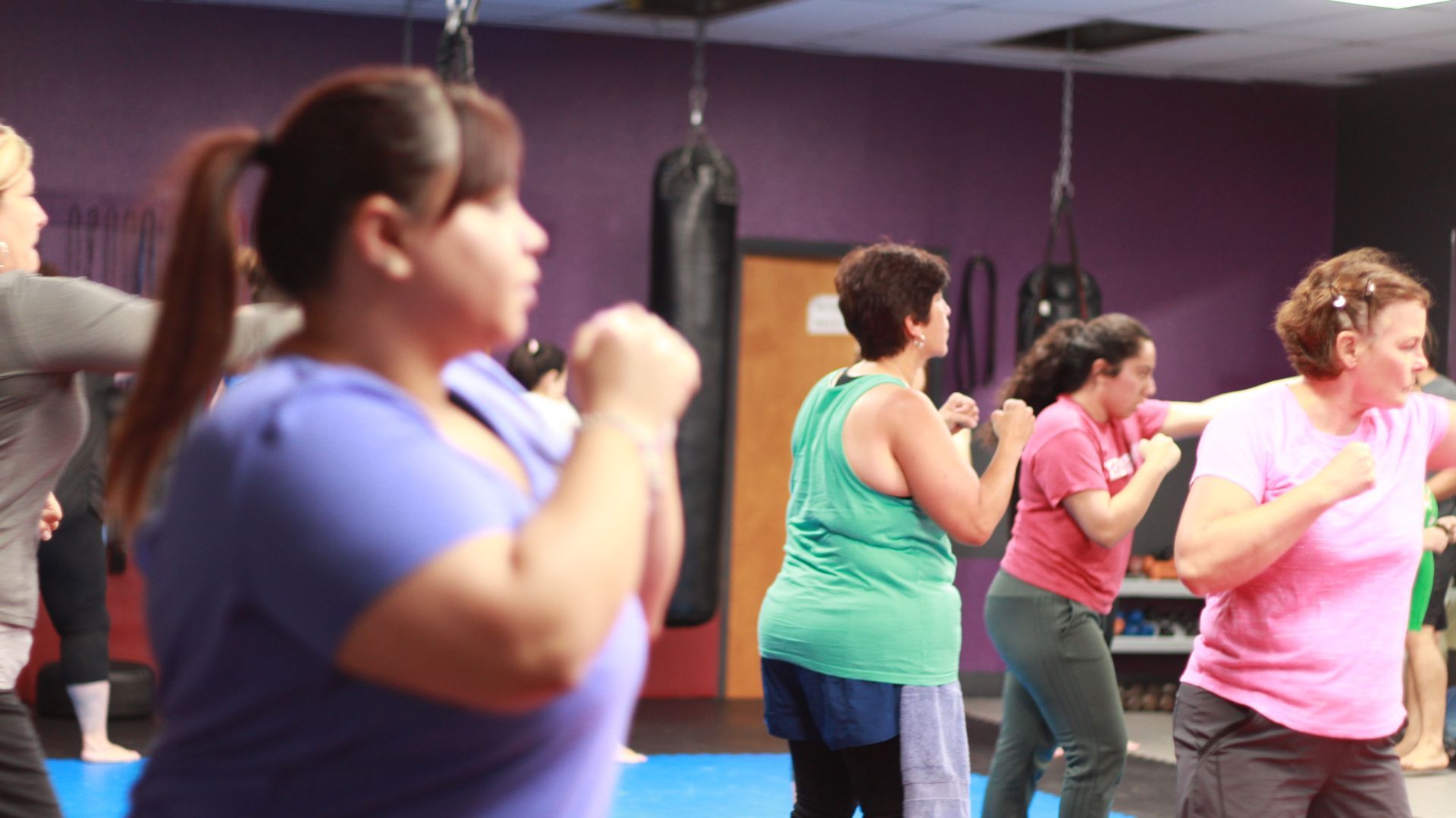 Two boys in karate uniforms sparring, kicking and punching with red and blue gloves.