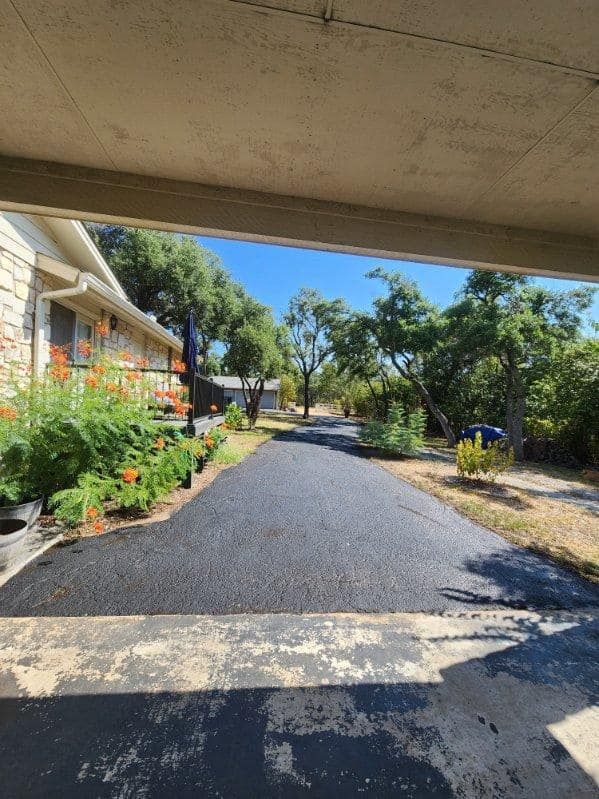 a view of a driveway from a garage with a house in the background