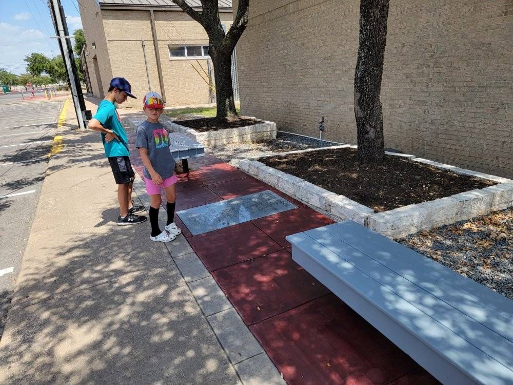 a man and a girl are standing on a sidewalk next to a bench