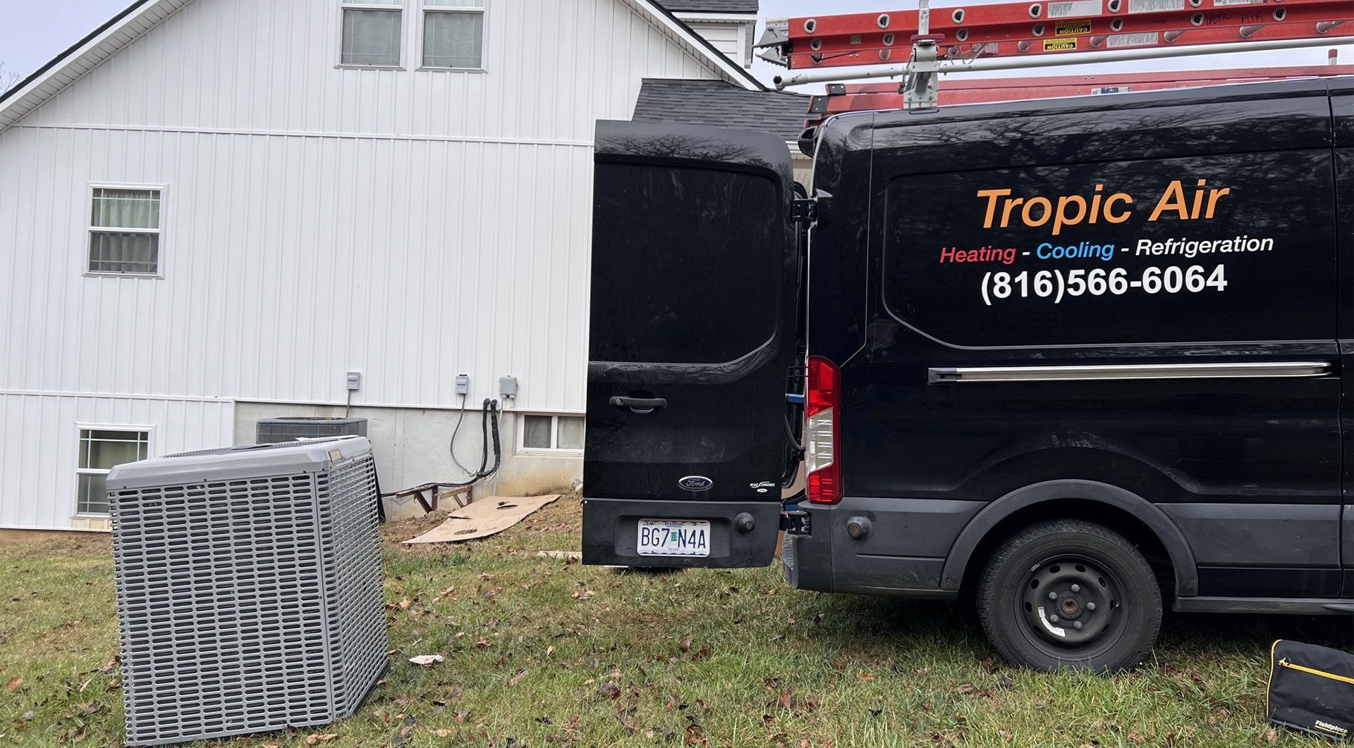 A black van is parked in front of a white house.