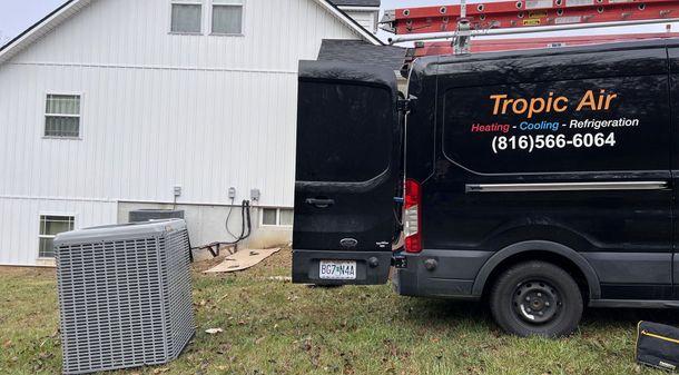 A black van is parked in front of a white house.