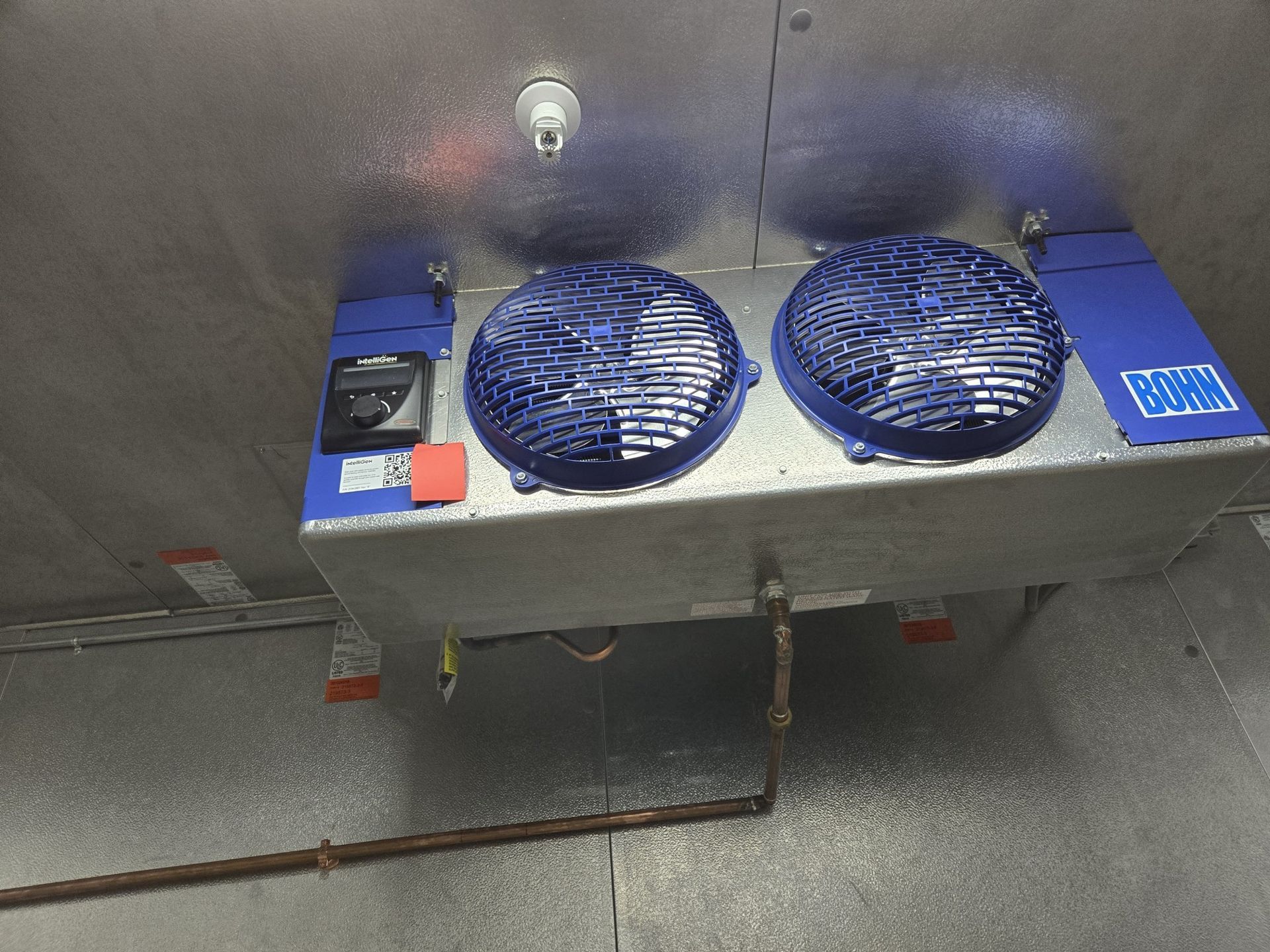 Two blue fans are mounted to a wall in a room.