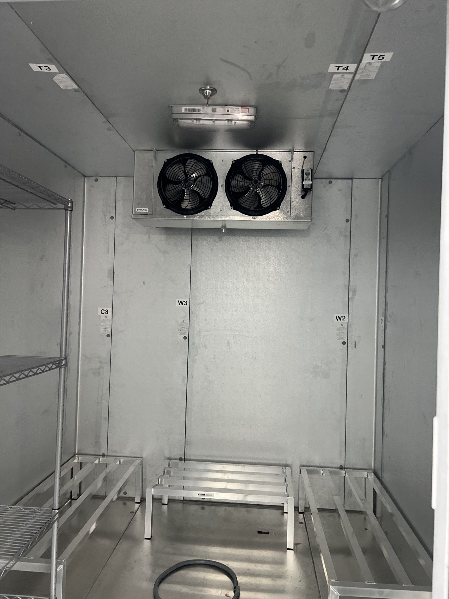 The inside of a refrigerator with two fans on the ceiling