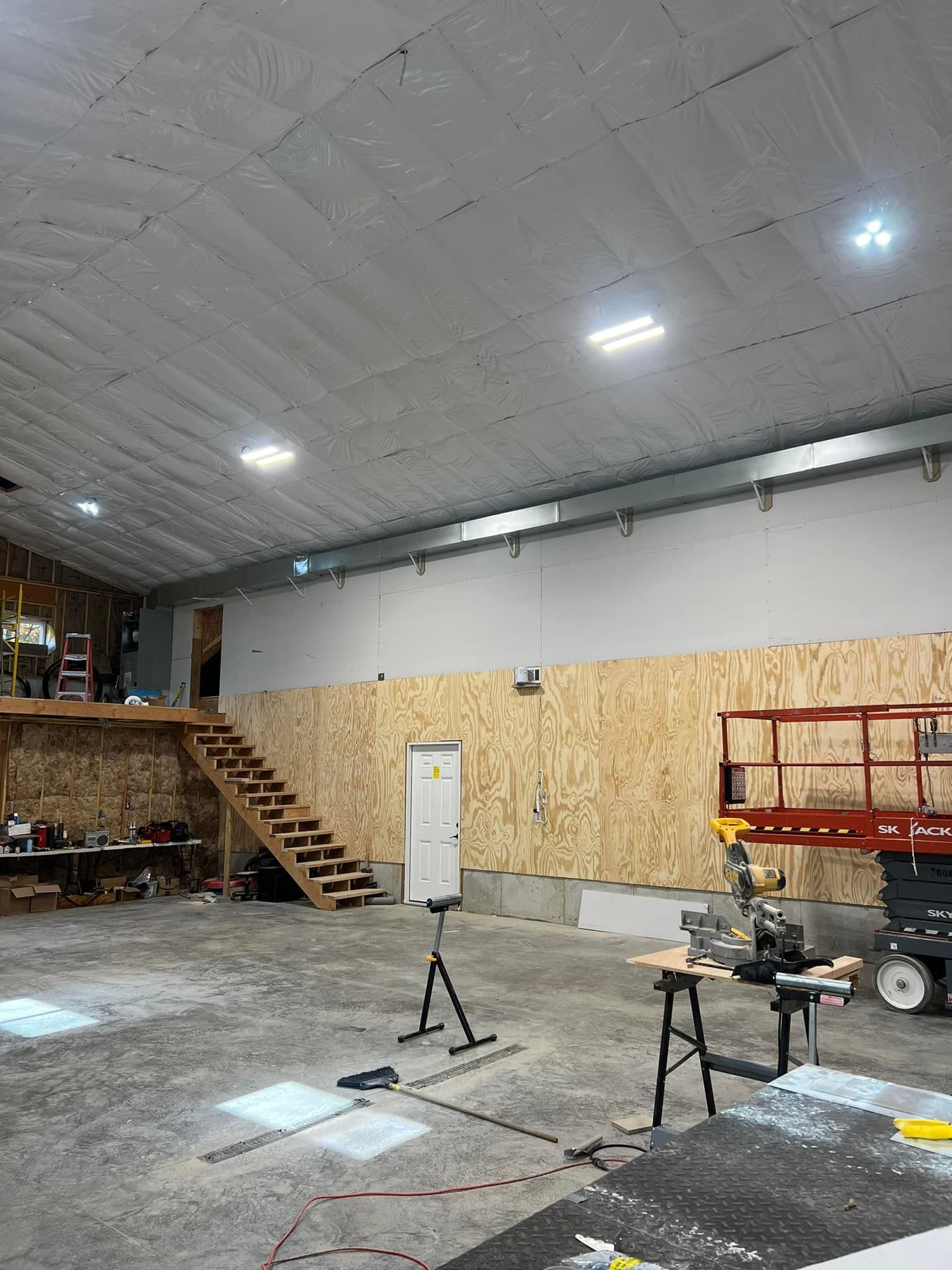 A large warehouse with a staircase and a lift in it.