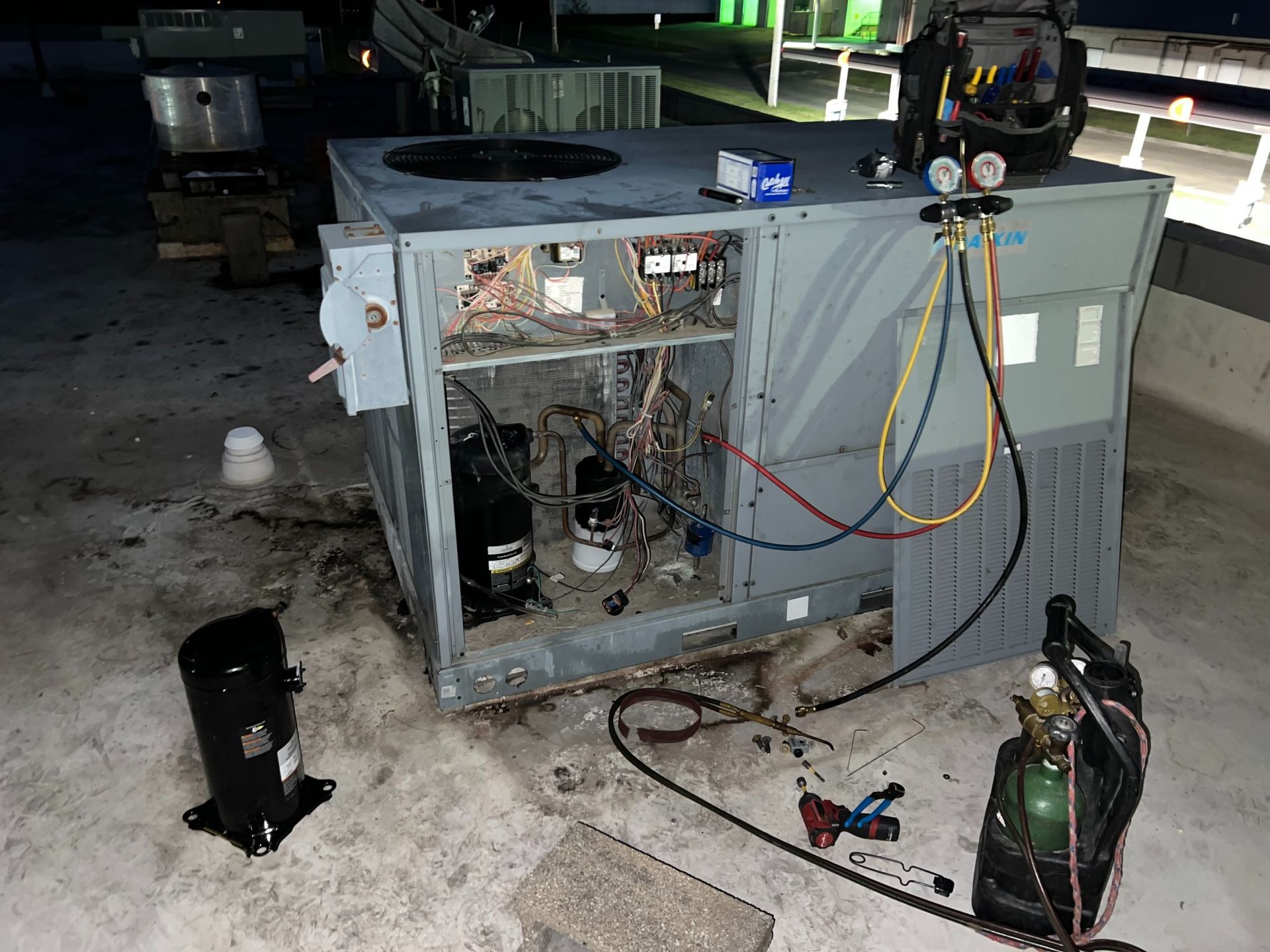 An air conditioner is being repaired on the roof of a building.