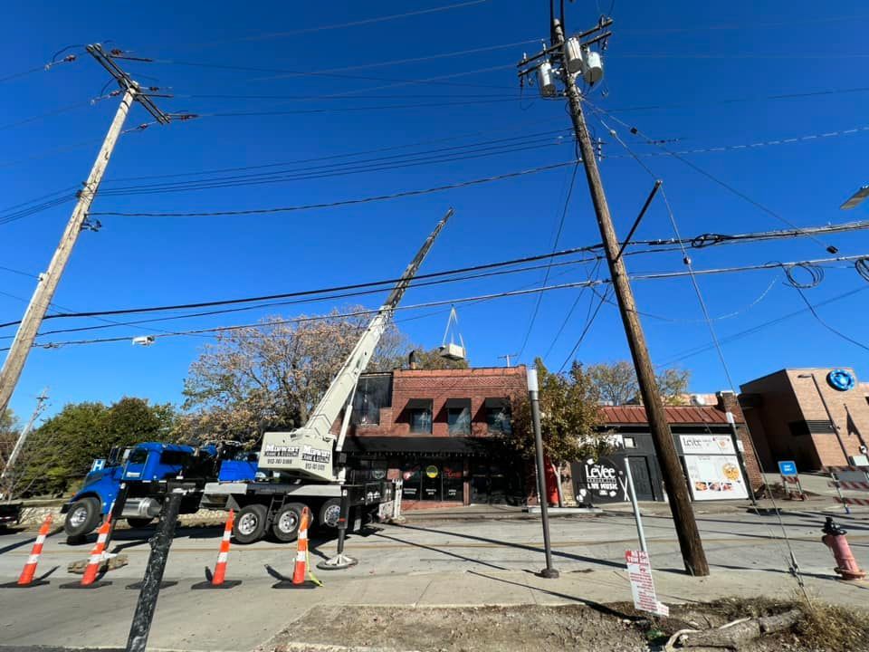 A crane is working on a power line in front of a building.
