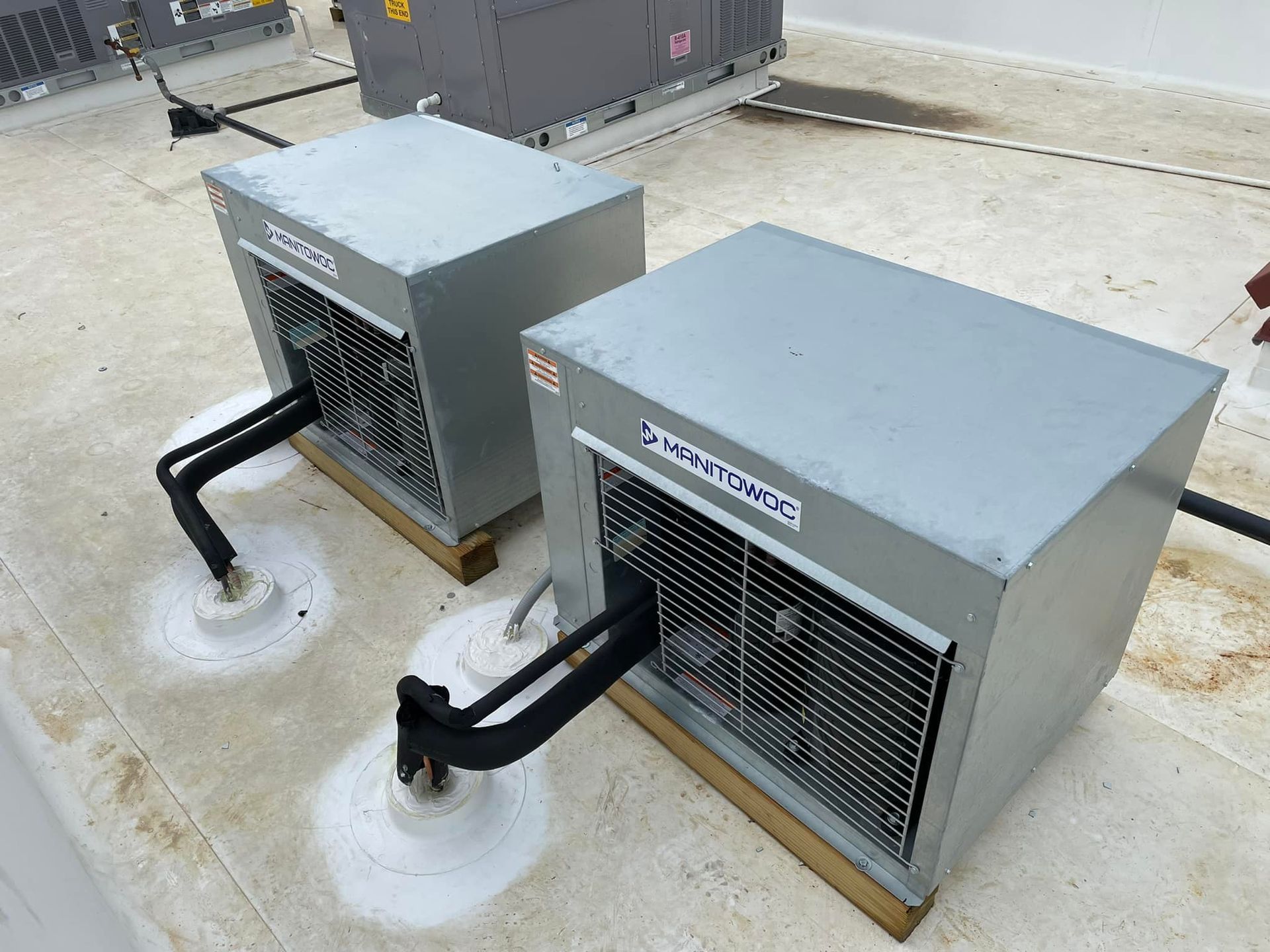 Two air conditioners are sitting on top of a roof.