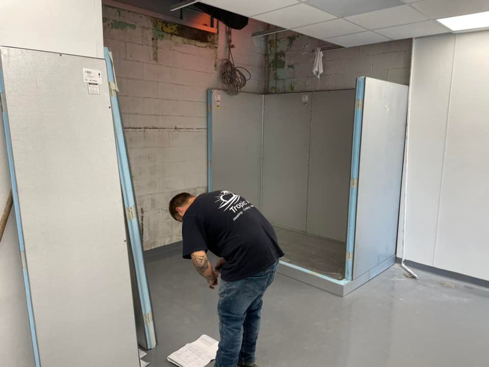 A man is kneeling down in a room with a mop.