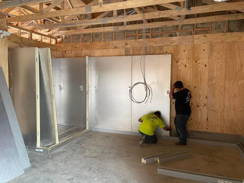 Two men are working on a wall in a room under construction.