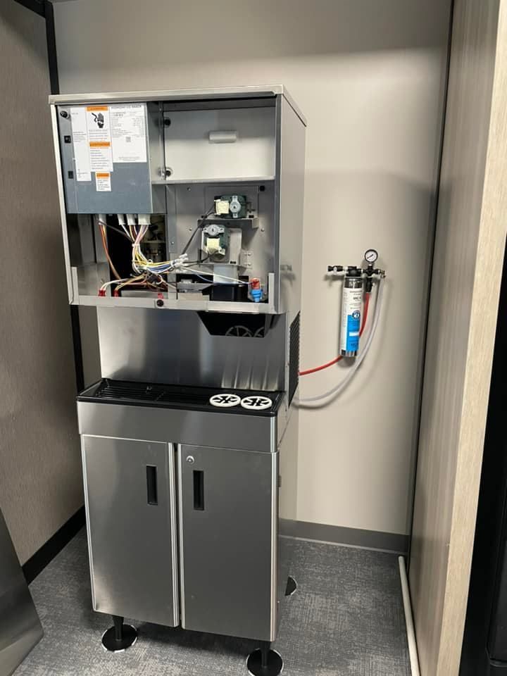 A stainless steel coffee maker is sitting in a room next to a wall.