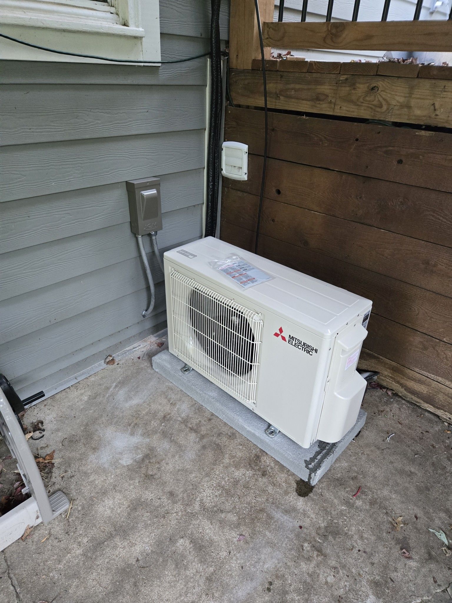 A white air conditioner is sitting on the side of a house.