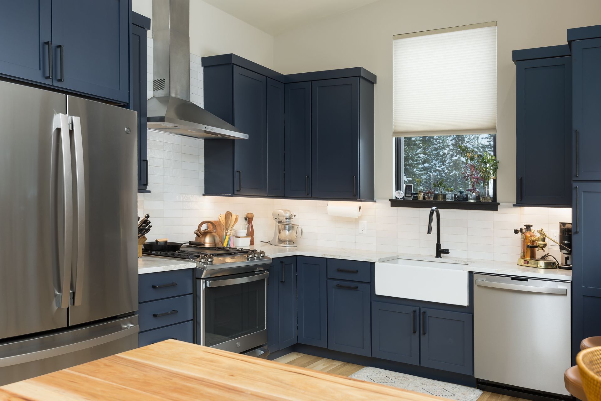 Navy blue kitchen with stainless steel appliances and a white farmhouse sink.