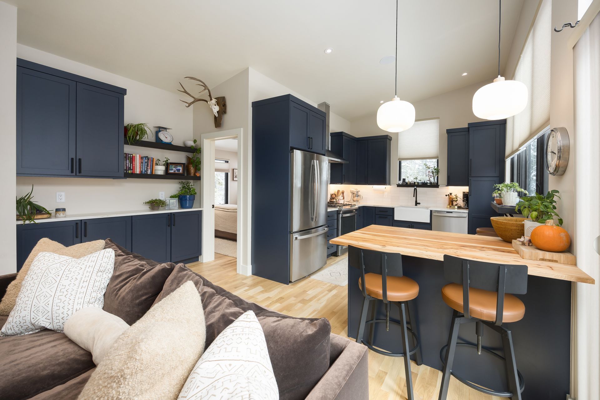 Navy blue kitchen with wooden countertop, stainless steel appliances, and a brown couch.