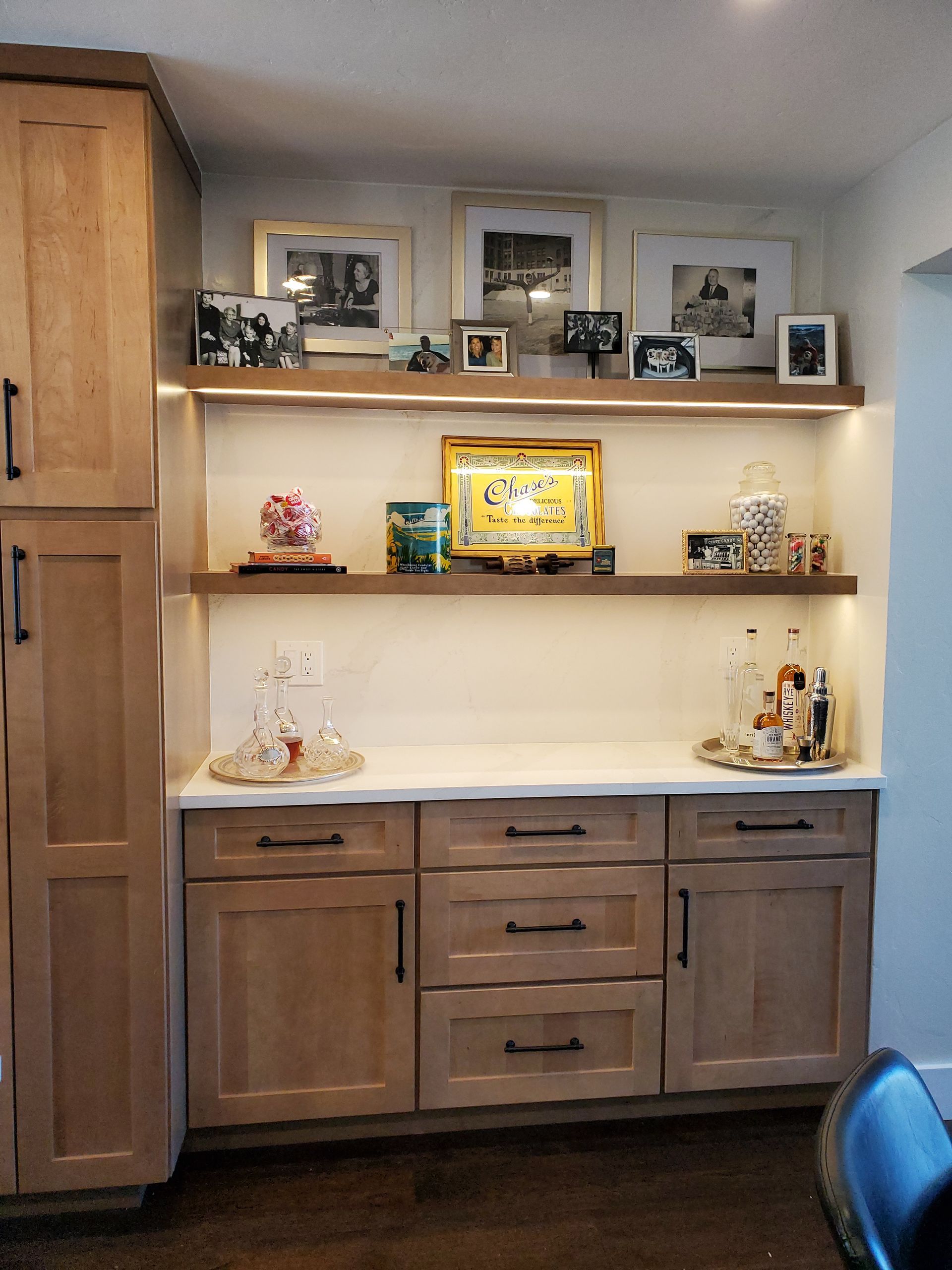 Built-in cabinet with shelves, backlit, displaying photos, decor, and liquor bottles.