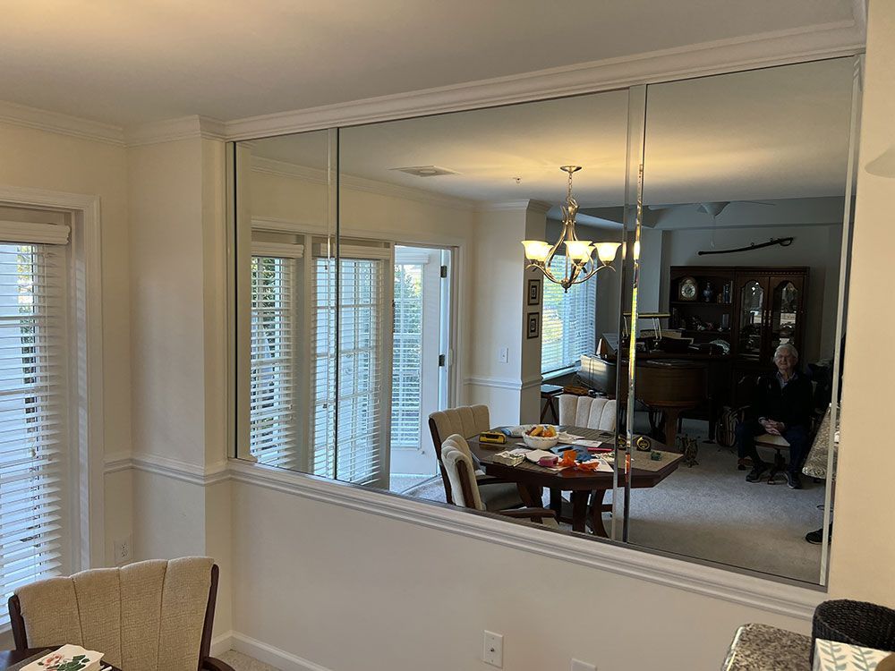A living room with a dining room table and chairs behind a large mirror.