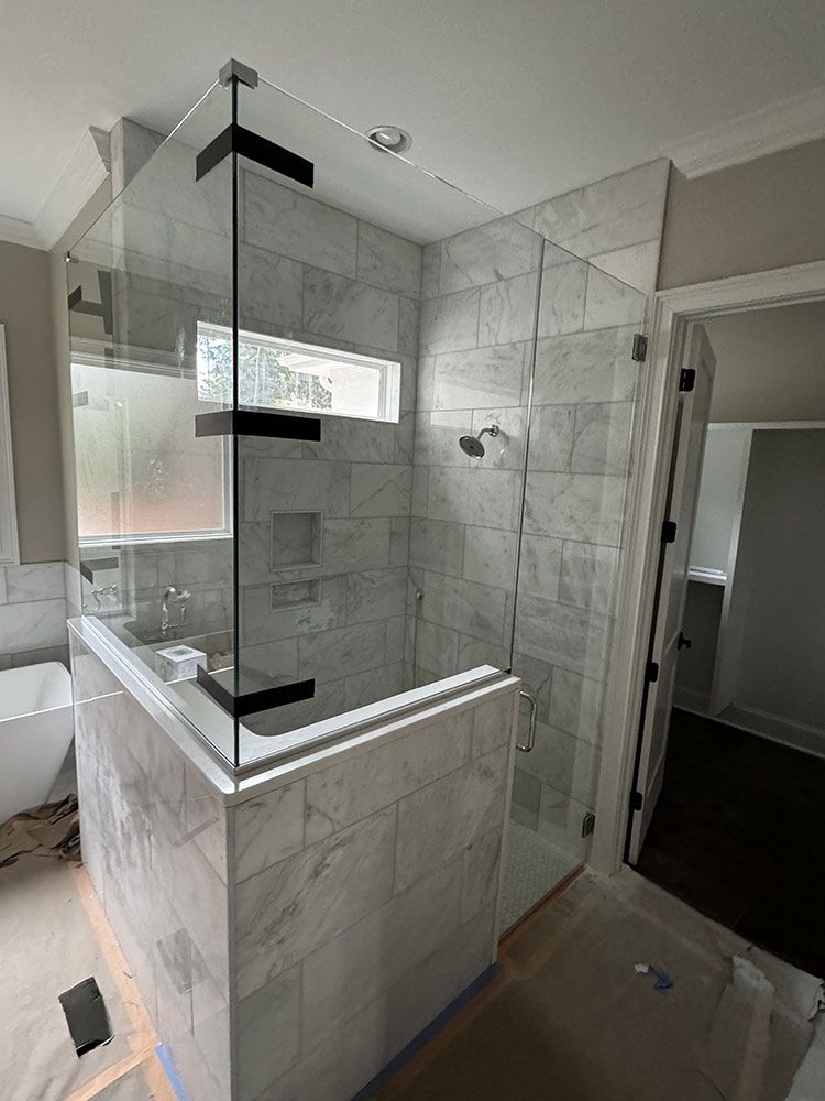 A bathroom with a walk in shower with a glass door.