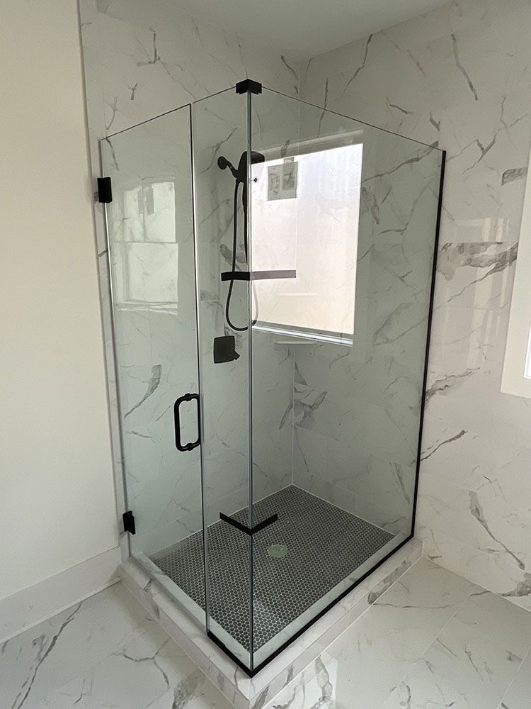 A bathroom with a shower stall and a window.