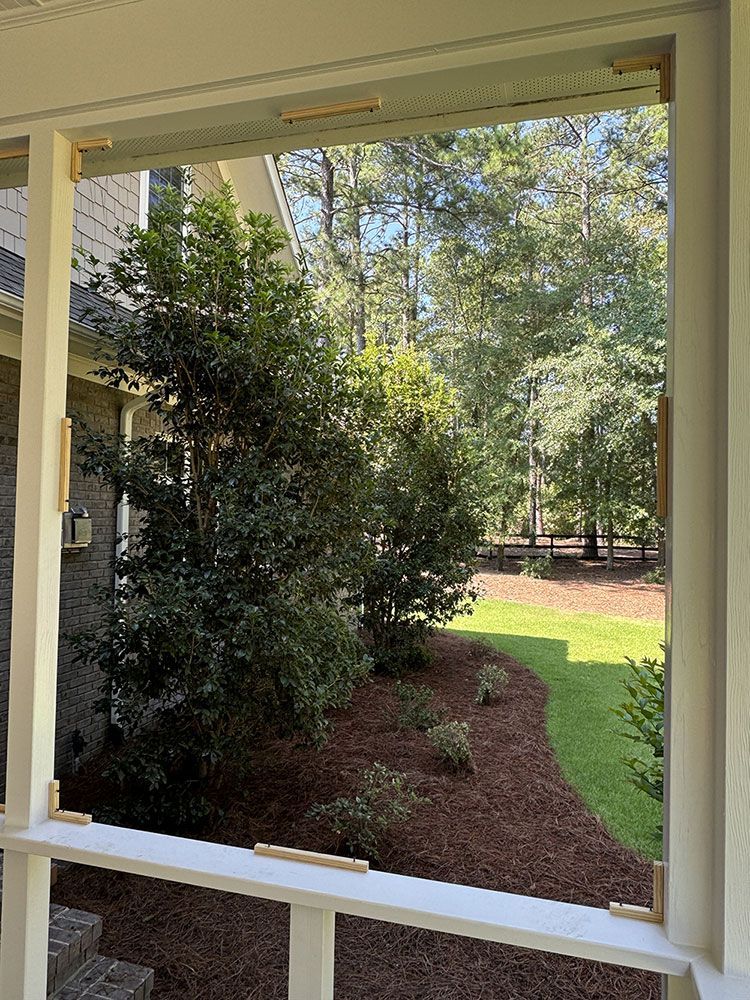 A screened in porch with a view of a yard and trees.